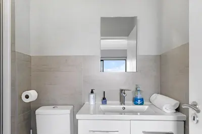 a white bathroom with a sink and a mirror at Two Bedroom Luxury Apartment, Century City - BackUp Power in Cape Town