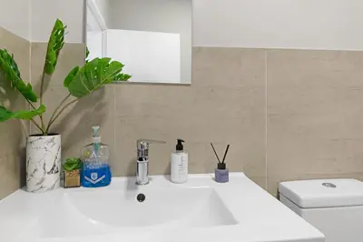 a bathroom with a white sink and a toilet at Two Bedroom Luxury Apartment, Century City - BackUp Power in Cape Town