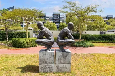 two statues of two people sitting on top of a field at Two Bedroom Luxury Apartment, Century City - BackUp Power in Cape Town