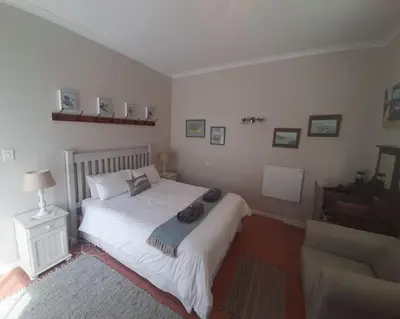 a bedroom with a white bed and a chair at Voëlklip garden flat in Hermanus