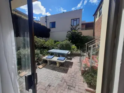a patio with a bench in front of a building at Voëlklip garden flat in Hermanus