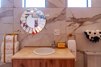 a bathroom with a sink and a mirror on the wall at The Glass Castle Retreat in Sir Lowry Pass