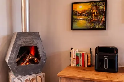 a woodburning stove sitting on a table with books at The Glass Castle Retreat in Sir Lowry Pass