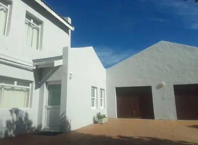 a white house with two garage doors on it at Heaven's Door in Bettyʼs Bay