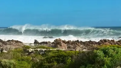 a large wave in the ocean on a rocky beach at Heaven's Door in Bettyʼs Bay