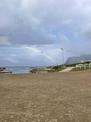 a rainbow in the sky over a beach with the ocean at Shekinah at Sea in Kleinmond