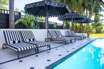 three chairs and an umbrella next to a swimming pool at Coco Queen in Paarl
