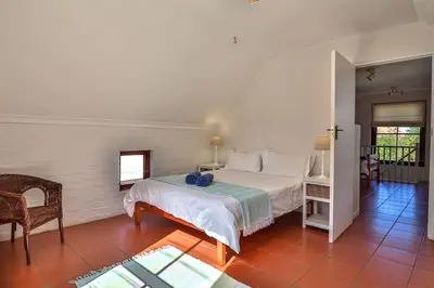 a bedroom with a bed and a table and a chair at Hilbre House in Bettyʼs Bay