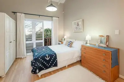 a bedroom with a bed and a dresser and a window at Whispering Waves in Hermanus