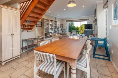 a kitchen and dining room with a wooden table and chairs at Whispering Waves in Hermanus