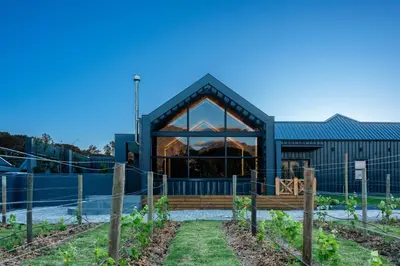 a greenhouse in a garden with a blue building at The Glass Castle in Sir Lowry Pass