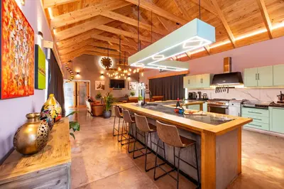an open kitchen with a large island with bar stools at The Glass Castle in Sir Lowry Pass