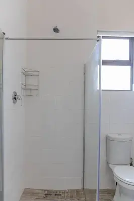 a bathroom with a toilet and a glass shower at Lux Private Garden Studio - Sunset Beach in Cape Town