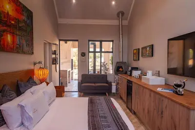 a living room with a large bed and a television at Golden Sunset Room in Sir Lowry Pass
