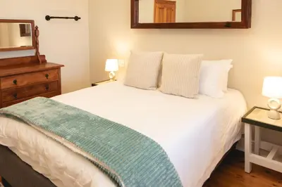 a bedroom with a white bed with a mirror and a dresser at The View Guesthouse & Cottage in Caledon