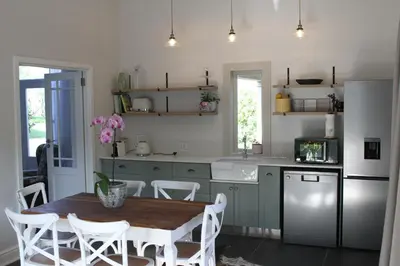 a kitchen with a table and a refrigerator at Jakaranda Cottage in Somerset West