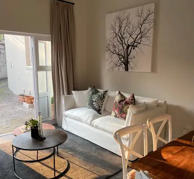 a living room with a white couch and a table at Jakaranda Cottage in Somerset West