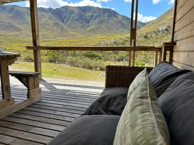 a couch on a porch with a view of mountains at The River Retreat Kogelberg in Kleinmond