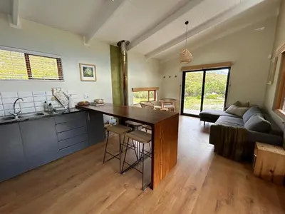 a kitchen and living room with a table and a couch at The River Retreat Kogelberg in Kleinmond