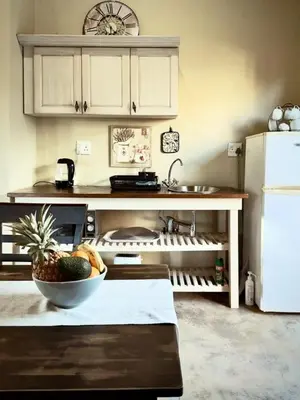 a kitchen with a bowl of fruit on a table at Simunye Cottage in Simondium
