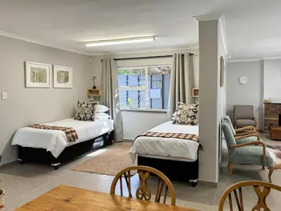 a bedroom with two beds and a living room at Stones - Cape Town Self Catering in Cape Town