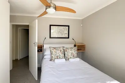 a bedroom with a bed with a ceiling fan at Stones - Cape Town Self Catering in Cape Town