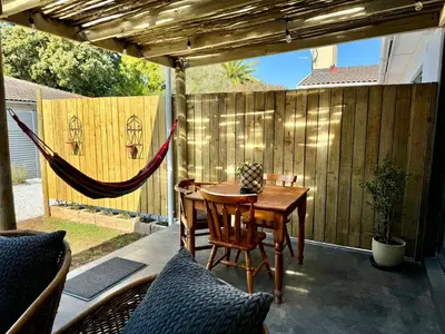 a patio with a table and chairs and a hammock at Stones - Cape Town Self Catering in Cape Town