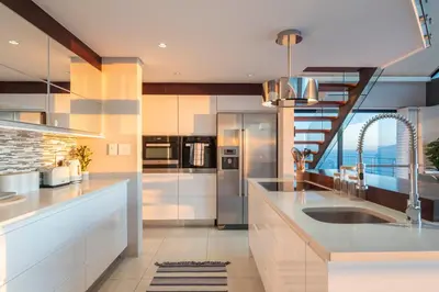 a kitchen with white cabinets and a view of the ocean at Penthouse with a view to die for! in Cape Town