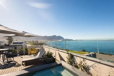 a swimming pool with a view of the ocean at Ocean Family Deluxe, Hermanus Waterfront Apartments in Hermanus