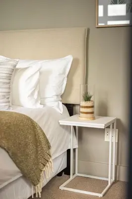 a bed with a side table with a cake on it at Ocean Family Deluxe, Hermanus Waterfront Apartments in Hermanus