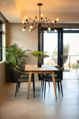 a dining room with a table and chairs and a chandelier at Ocean Family Deluxe, Hermanus Waterfront Apartments in Hermanus