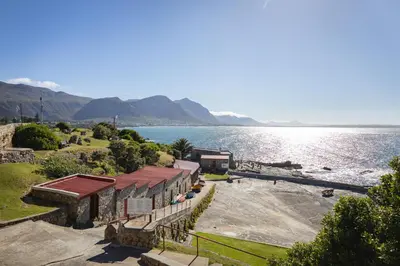 a building on the shore of a body of water at Ocean Family Deluxe, Hermanus Waterfront Apartments in Hermanus