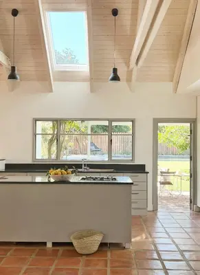 a kitchen with a large island in a room with windows at Kumbuk House in Franschhoek