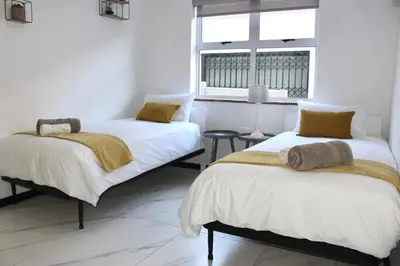 two beds in a white room with a window at Sea and Mountain View Apartment in Cape Town