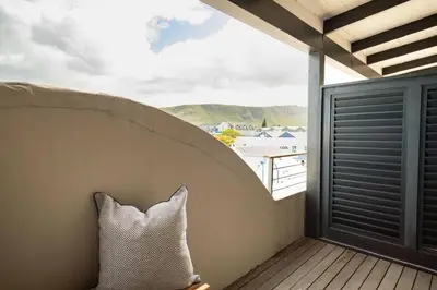 a pillow sitting on a balcony with a view at Studio 7 - Hermanus Waterfront Apartments in Hermanus