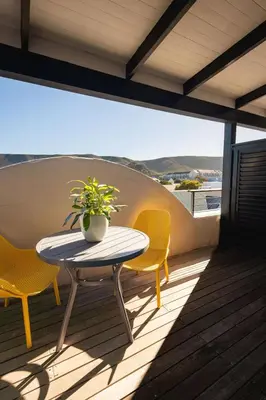 a table and two chairs on a balcony with a plant at Studio 7 - Hermanus Waterfront Apartments in Hermanus