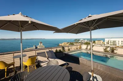 a balcony with a swimming pool and chairs and umbrellas at Studio 7 - Hermanus Waterfront Apartments in Hermanus