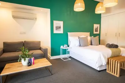a bedroom with a bed and a couch and a table at Studio 7 - Hermanus Waterfront Apartments in Hermanus