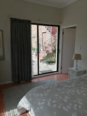 a bedroom with a bed and a large window at Voëlklip Garden Flat in Hermanus
