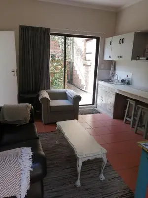 a living room with a couch and a table at Voëlklip Garden Flat in Hermanus