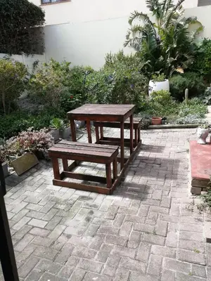 a picnic table and bench on a brick patio at Voëlklip Garden Flat in Hermanus