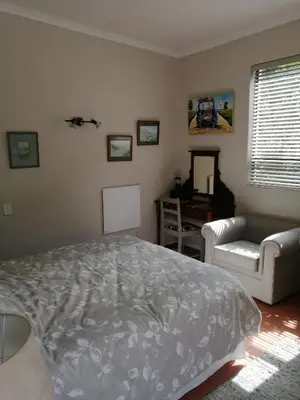 a bedroom with a bed and a couch at Voëlklip Garden Flat in Hermanus