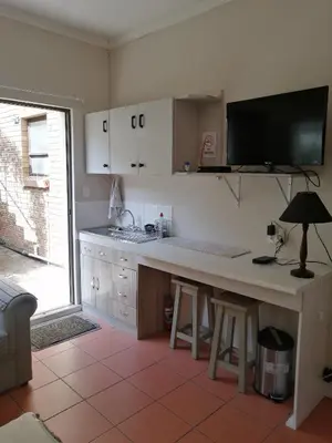 a kitchen with a large white counter and a table at Voëlklip Garden Flat in Hermanus