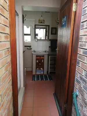 a hallway leading to a kitchen with a sink at Voëlklip Garden Flat in Hermanus
