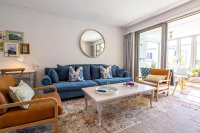 a living room with a blue couch and a table at Waddle Inn Luxury apartment in Franschhoek in Franschhoek