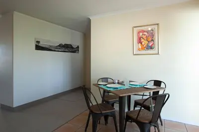 a dining room with a table and four chairs at Luxury Studio sleeps up to 3 adults - Sunset Beach in Cape Town