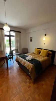 a bedroom with a large bed and a living room at Retro City Center Gem by ARPA Hospitalities in Stellenbosch