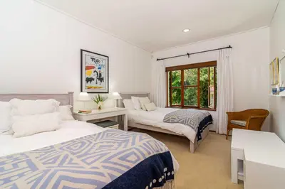 a bedroom with two beds and a desk and a window at Fynbos House in Hermanus