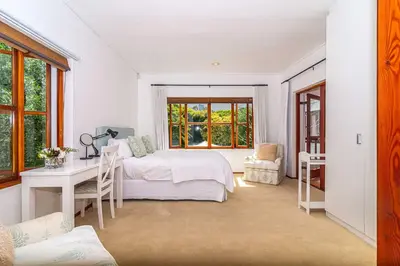 a bedroom with a bed and a desk and a window at Fynbos House in Hermanus
