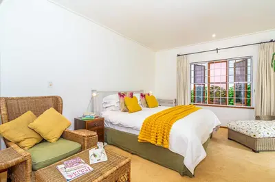 a bedroom with a bed and a chair and a window at Fynbos House in Hermanus